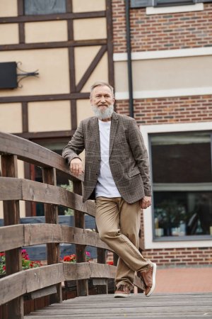 happy bearded and senior man standing on wooden bridge, positive, urban life, elderly, full length