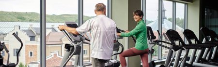 active seniors, cheerful woman looking at elderly man, exercising together, senior couple, banner
