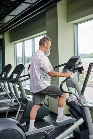 Photo for Bearded senior man working out on stepper exercise machine, elderly in gym, active senior, sport - Royalty Free Image