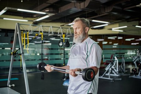 atlético anciano con barba ejercitando con barbell en gimnasio, senior activo, atleta, fuerza