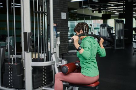 femme âgée forte et motivée travaillant dans la salle de gym, fitness mature, machine d'exercice, active