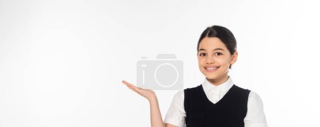 joyeuse écolière montrant quelque chose avec la main, pointant et regardant la caméra, présentant, bannière