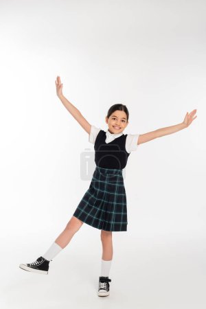 excited schoolgirl standing with outstretched hands isolated on white, full length, happiness