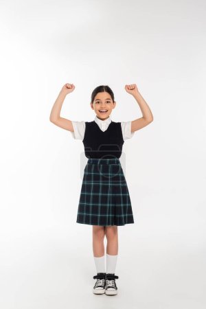 Foto de Emoción, colegiala feliz celebrando de nuevo a la escuela, aislado en blanco, longitud completa, uniforme - Imagen libre de derechos