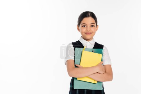 Photo for Happy schoolgirl standing with notebooks in hands and looking at camera isolated on white, student - Royalty Free Image