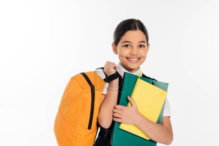 Téléchargez les photos : Heureuse écolière debout avec des cahiers dans et sac à dos dans les mains, nouveau concept de l'année scolaire, élève - en image libre de droit