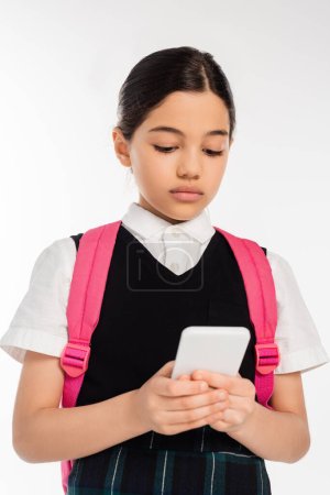 digital age, schoolgirl with backpack using smartphone isolated on white, student in uniform