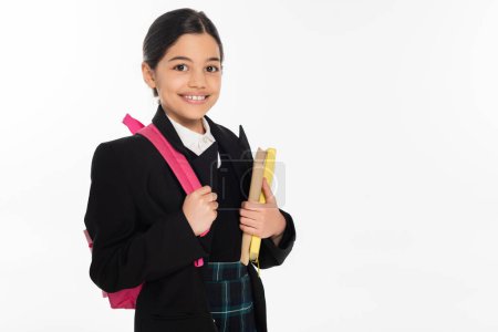 cheerful schoolgirl standing with notebooks and backpack isolated on white, back to school concept