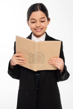 glücklich Schulmädchen in Uniform Lesebuch, Student mit brünetten Haaren isoliert auf weißem, intelligentes Mädchen