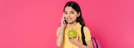 happy schoolgirl standing with backpack, holding apple and talking on smartphone, phone call, banner