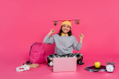 happy girl in beanie hat sitting with penny board on head, laptop, headphones, apple,  alarm clock Poster #670362994