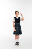 full length, positive schoolkid in uniform pointing up and looking at camera on white, girl in skirt Sweatshirt #670363776