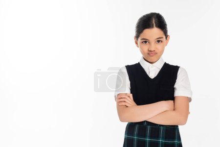 Porträt, beleidigtes Schulmädchen in Uniform, das in die Kamera blickt und mit verschränkten Armen auf weiß steht