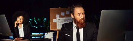 Photo for Bearded man working at night in office near tempting african american woman on background, banner - Royalty Free Image