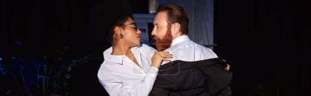 young african american businesswoman embracing bearded man in night, seduction at work, banner