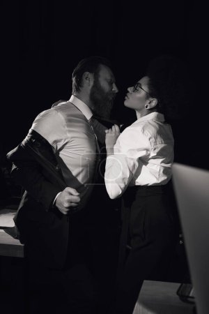 Photo for Black and white image of passionate african american woman near bearded businessman, office romance - Royalty Free Image