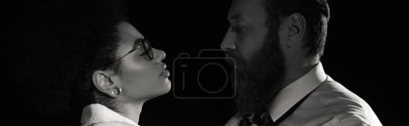 Photo for Passionate interracial couple looking at each other at night in office, monochrome image, banner - Royalty Free Image