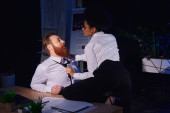 young african american businesswoman pulling tie of bearded businessman at work desk, office romance puzzle #670962852