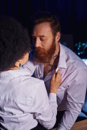 african american woman tempting bearded tattooed businessman in office at night, flirting at work