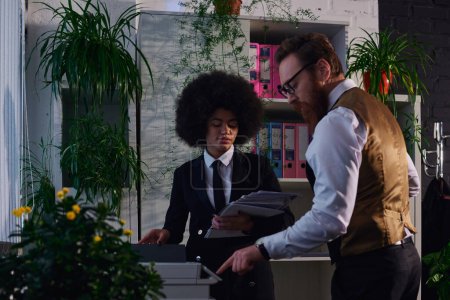 bearded businessman showing african american secretary with documents how to use copier in office