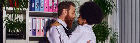 couple interracial embrassant dans la soirée près de rack avec des dossiers le soir, amour au travail, bannière