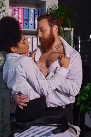 seductive african american woman undressing bearded tattooed businessman, seduction in night office