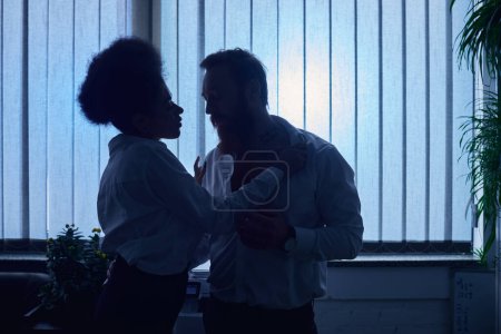 Liebe im Nachtbüro, dunkle Silhouette einer leidenschaftlichen Afroamerikanerin, die mit einem Kollegen flirtet