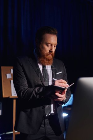 bearded businessman in elegant formal wear writing in notebook while working in office at night