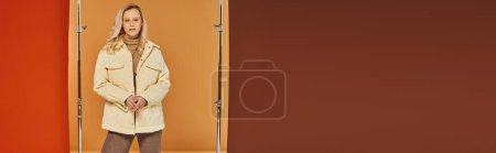 Téléchargez les photos : Concept de mode d'automne, femme blonde en veste chaude posant sur fond orange, couches confortables, bannière - en image libre de droit