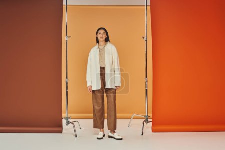 pretty asian model posing in autumn attire, leather pants and outerwear, multicolored backdrop
