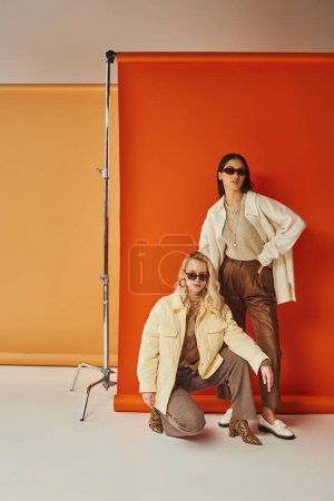 Mode und Stil, interrassische Models in Sonnenbrille und Oberbekleidung posieren im Studio, Herbstfarben