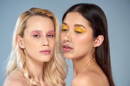 Verschiedene Schönheit, Porträt von zwei interrassischen Frauen mit kühnem Make-up posiert auf blauem Hintergrund
