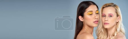 Téléchargez les photos : Beauté différente, portrait de femmes interracial avec un maquillage audacieux posant sur fond bleu, bannière - en image libre de droit