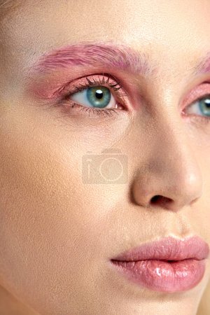 photo détaillée de jeune femme aux yeux bleus et maquillage des yeux rose détournant les yeux, gros plan