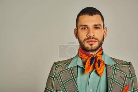 retrato de hombre serio en chaqueta a cuadros y pañuelo colorido en gris, moda de inspiración retro