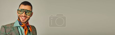 Téléchargez les photos : Portrait de l'homme heureux de style rétro en veste à carreaux et foulard avec des lunettes de soleil sur gris, bannière - en image libre de droit