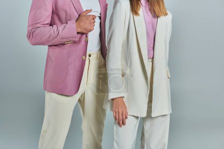 cropped view of young business couple in elegant suits standing on grey backdrop, classic fashion