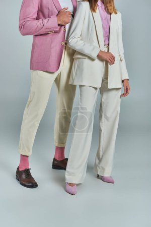 Ausgeschnittene Ansicht eines Paares in eleganter und stilvoller Businesskleidung, die auf grau-formaler Kleidung steht
