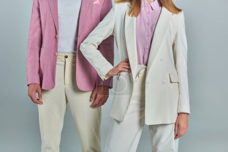cropped woman of woman with hand on hip near man in stylish lilac blazer on grey, trendy formal wear