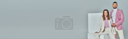 Téléchargez les photos : Jeune couple en tenue formelle à la mode posant près de cubes blancs sur fond de studio gris, bannière - en image libre de droit