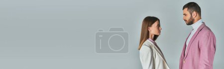 Téléchargez les photos : Vue latérale de jeune couple dans des blazers élégants se regardant sur le gris, la mode d'affaires, la bannière - en image libre de droit