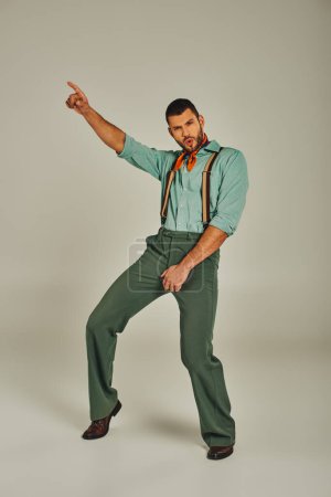 aufgeregter Mann in Retro-Klamotten und Hosenträgern, der mit dem Finger zeigt und auf grauen Ganzkörperanzügen tanzt