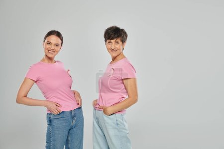 Brustkrebs-Konzept, Unterstützungskampagne, zwei Frauen, die in die Kamera schauen, Lächeln, graue Kulisse