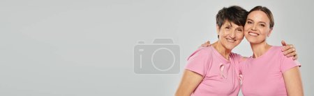 Brustkrebs-Konzept, glückliche Frauen, die in die Kamera schauen und sich vor grauem Hintergrund umarmen, Unterstützung, Banner