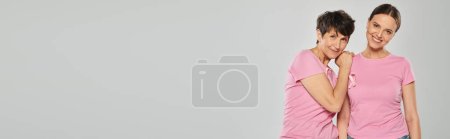breast cancer awareness concept, two women with pink ribbons on grey backdrop, cancer free, banner