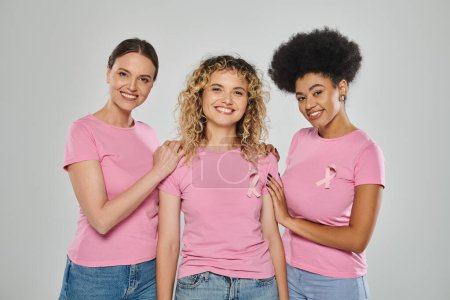 Foto de Concienciación sobre el cáncer de mama, felices cuatro mujeres interracial con cintas rosadas sobre fondo gris, diversa - Imagen libre de derechos