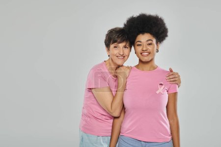 Foto de Concienciación sobre el cáncer de mama, mujeres multiculturales felices abrazándose en el telón de fondo gris, campaña de apoyo - Imagen libre de derechos