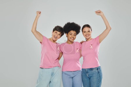 breast cancer awareness, excited interracial women on grey backdrop, different generations, portrait