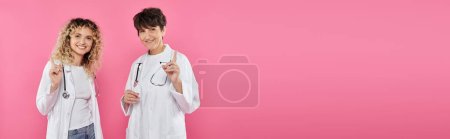 Foto de Doctores con batas blancas advirtiendo sobre el telón de fondo rosa, alegría, conciencia sobre el cáncer de mama, mujeres, pancarta - Imagen libre de derechos