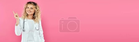 Téléchargez les photos : Concept de sensibilisation au cancer du sein, femme heureuse médecin pointant vers le haut, fond rose, joie, femme, bannière - en image libre de droit